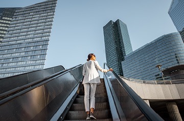 Woman ascending an outdoor escalator in a city