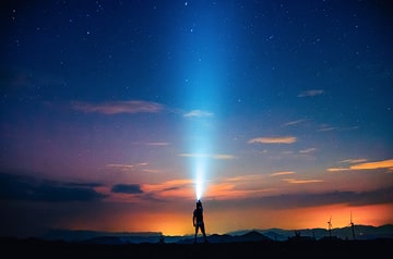 Hiker silhouette against evening sky with headlight shining