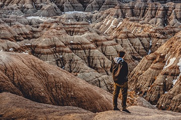 hiker heading down a trail in a badlands canyon