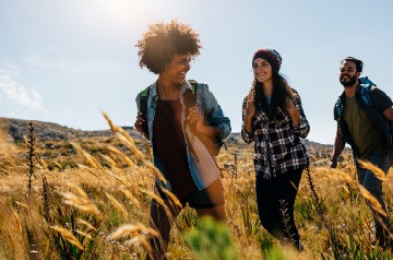 Three people hiking through field on sunny day