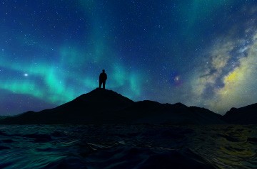 Stargazer silhouetted under the Aurora Borealis