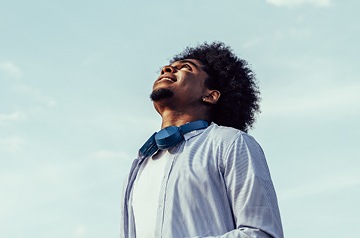 African American man looking up into a clear blue sky