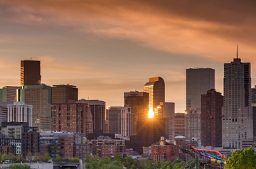 The setting sun shining between the tall buildings of the Denver skyline