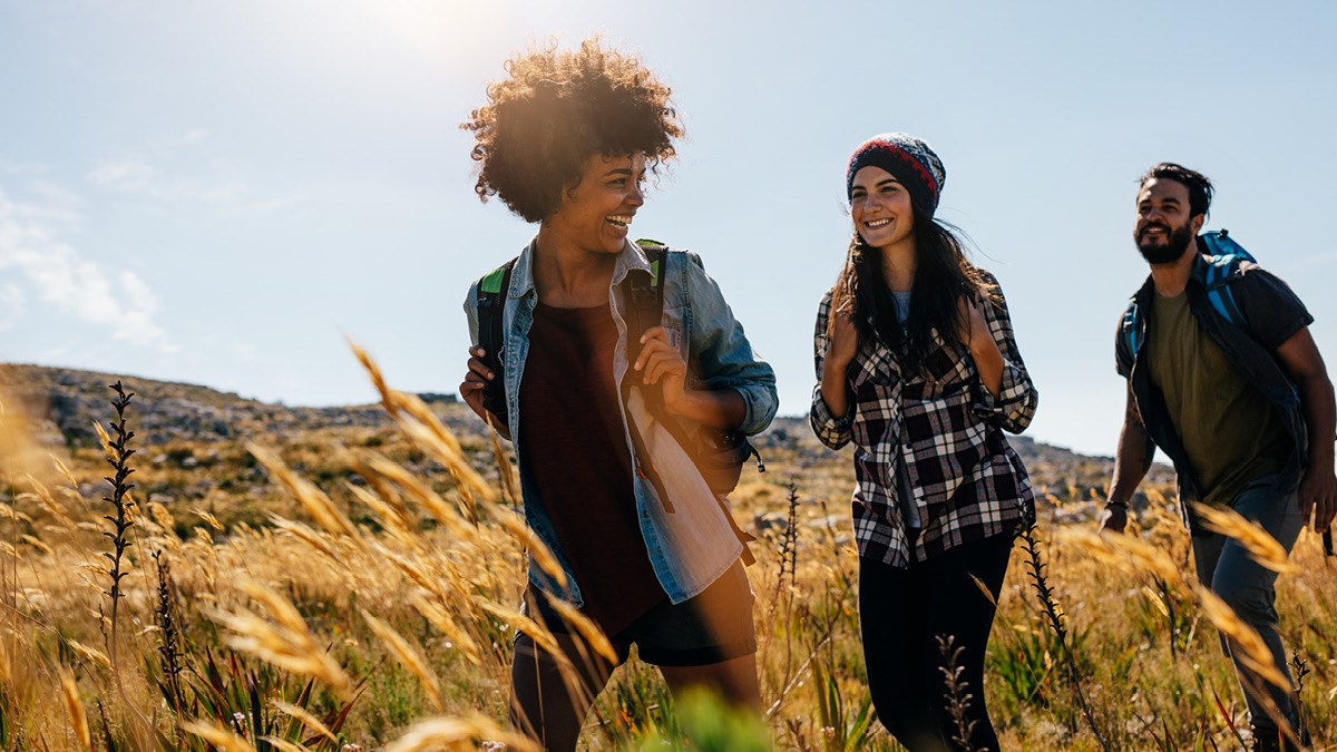 A smiling group of people walking through tall grass.