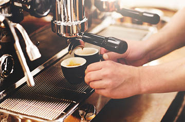Barista's hands pull two shots of espresso