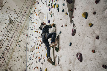 A rock climber scales the wall at an indoor training gym.