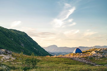 blue tent on a rocky mountain meadow