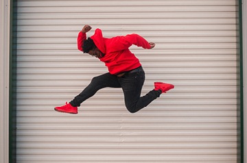 Portrait of stylish Black man in sportswear jumping