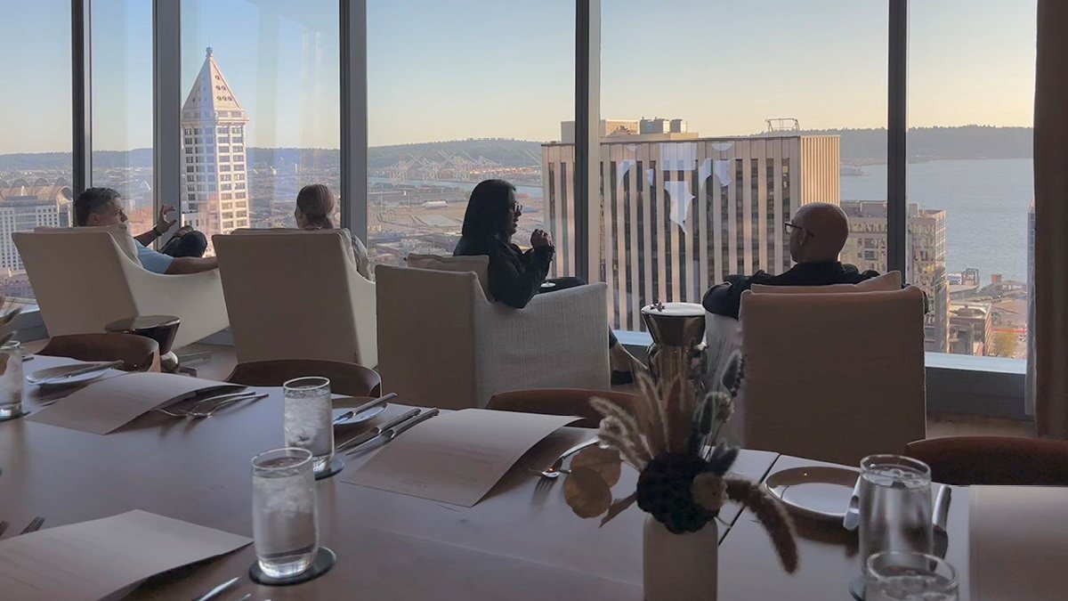 Colleagues meet in a conference room with a view of Smith Tower and Elliott Bay in Seattle