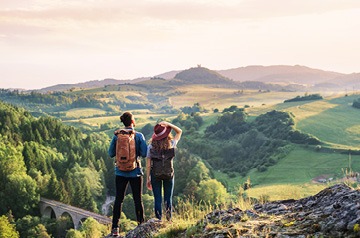 Two hikers looking out over rolling hills on a sunny day