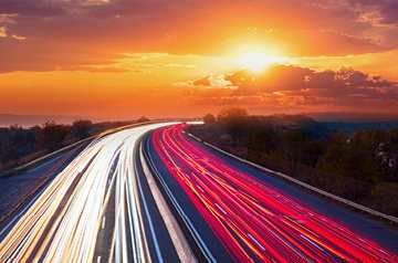 Busy highway, sun and clouds above