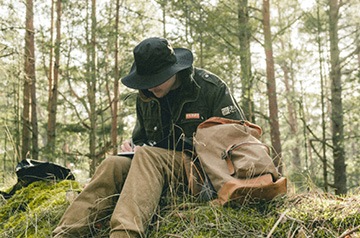 hiker sitting on log writing in notebook