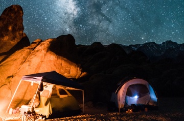 Two tents under a starry sky at a desert campsite