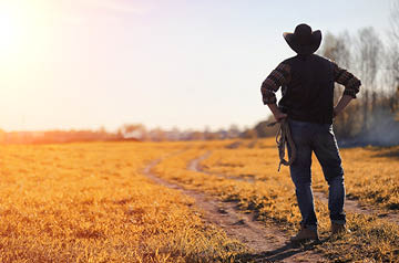 Person wearing lasso and hat looking out onto a field