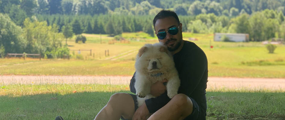 Parsa Dara on a sunny lawn holding a dog.