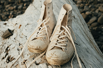 A pair of dirty shoes on a fallen tree