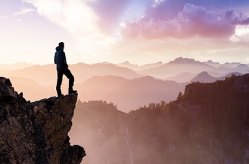 Person standing on outcropping looking over mountain range