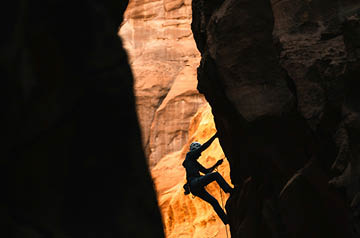 Rock climber backlit by sun against sandstone