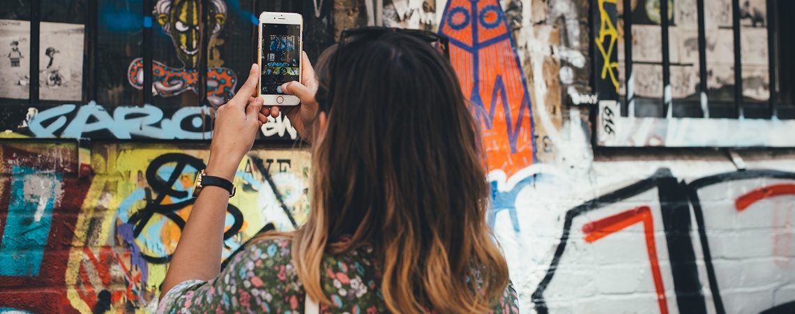 A woman taking a picture of a wall of graffiti