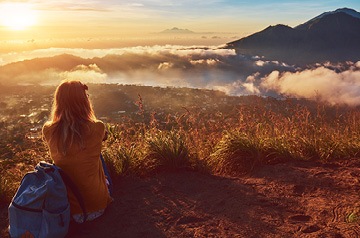 Woman on hillside looking over mountain range at dawn