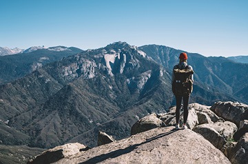 Hiker standing on rocks looking at mountain tops