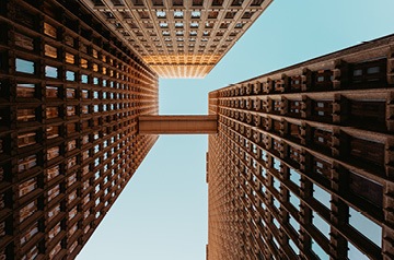 Looking skyward between buildings with windows making geometric patterns